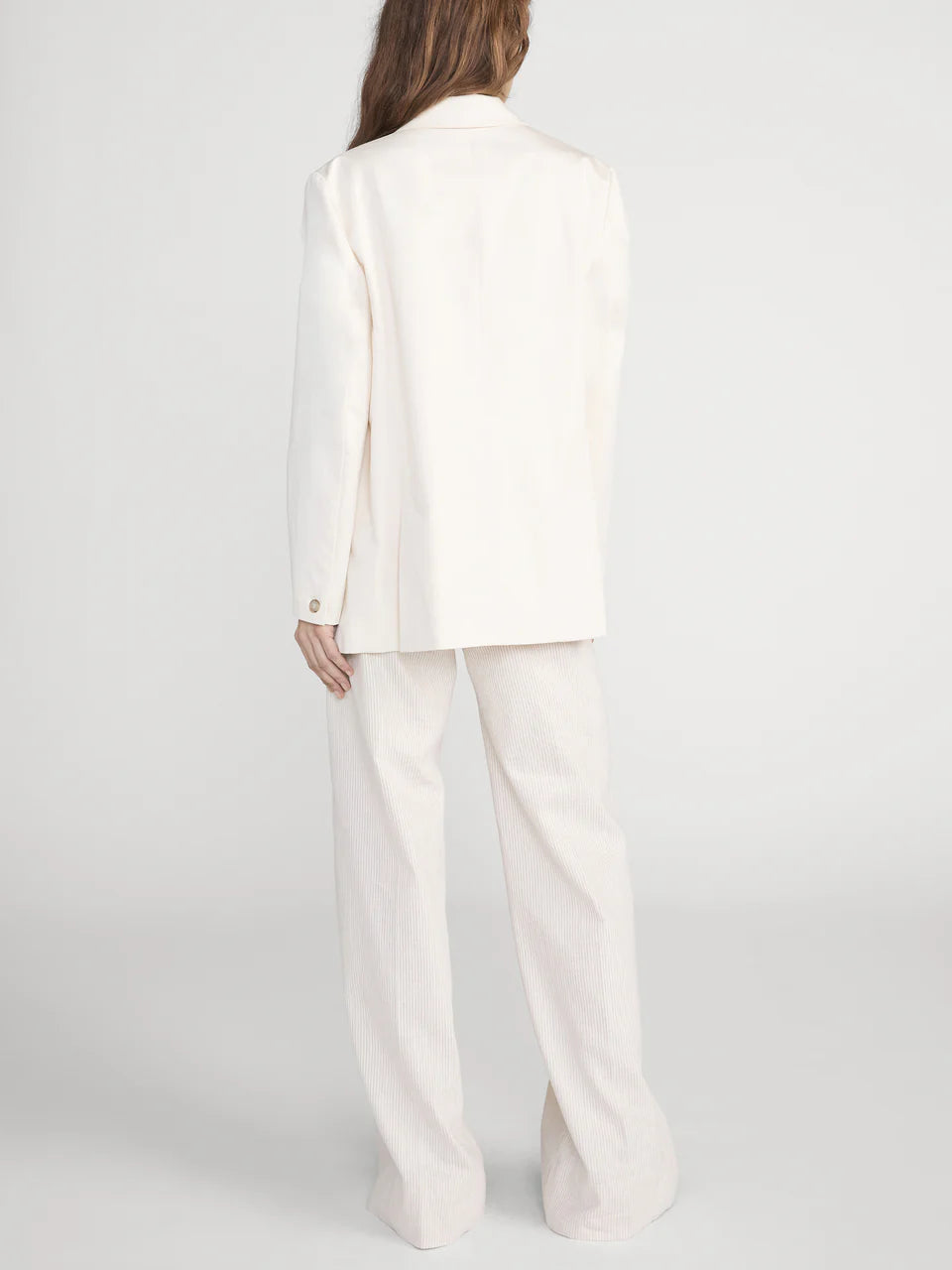 Person wearing a white suit on a plain background