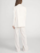 Person wearing a white suit on a plain background