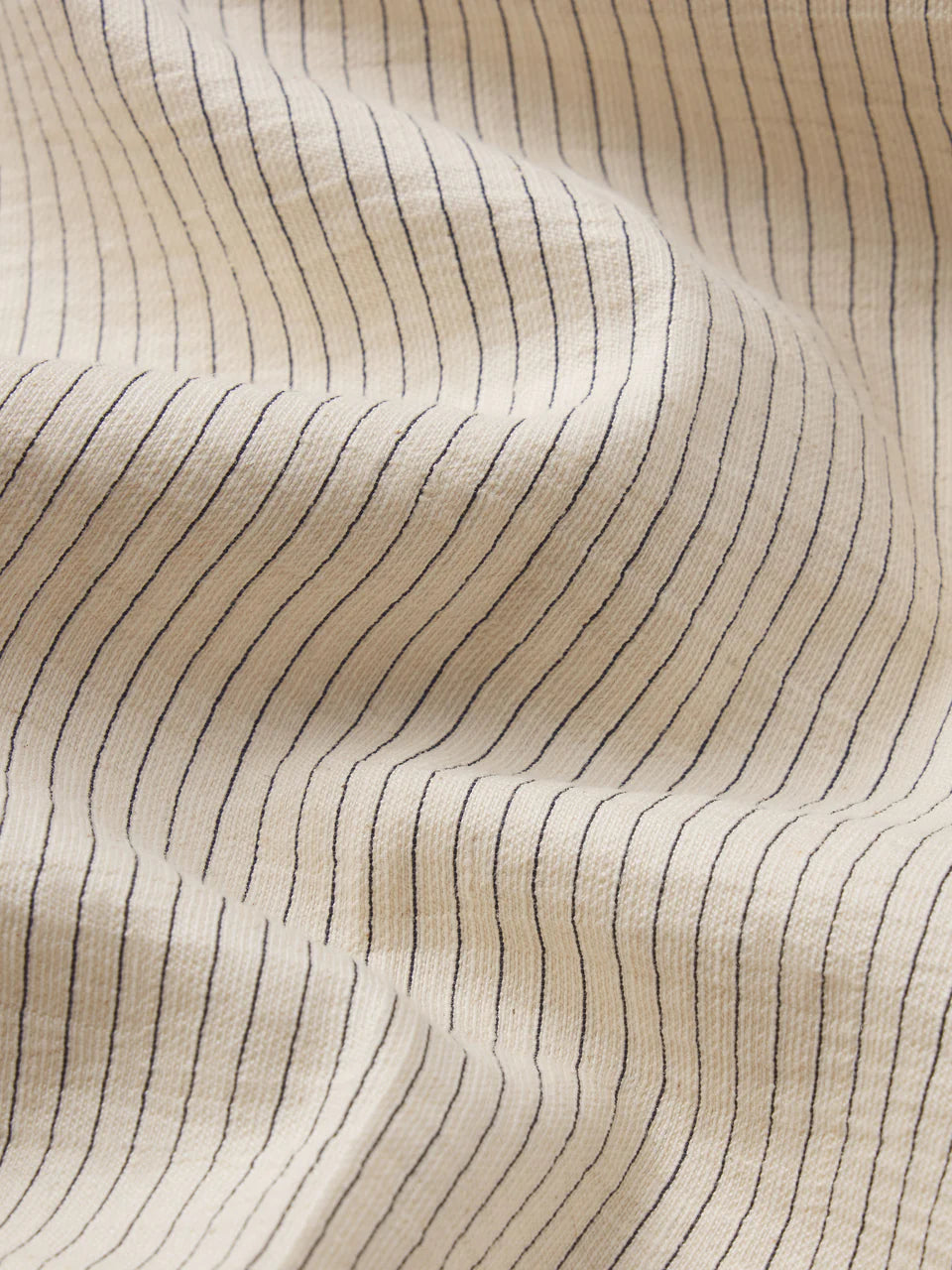 Close-up of beige fabric with subtle black line pattern