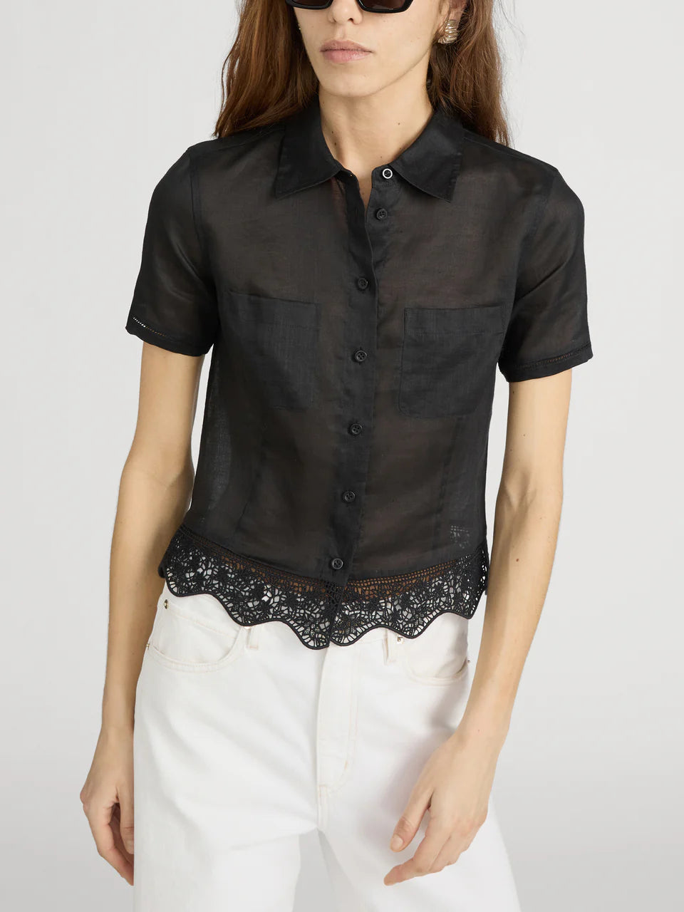 Black short-sleeve blouse with lace trim worn by a person on a white background