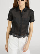 Black short-sleeve blouse with lace trim worn by a person on a white background
