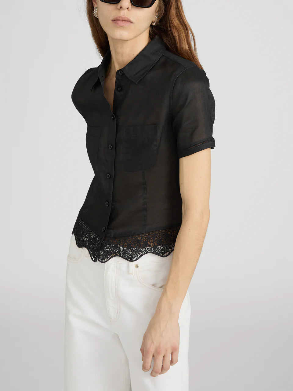 Woman wearing a black short-sleeve blouse with lace trim on a white background