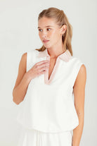 Woman wearing a white sleeveless top with a pink collar against a light background