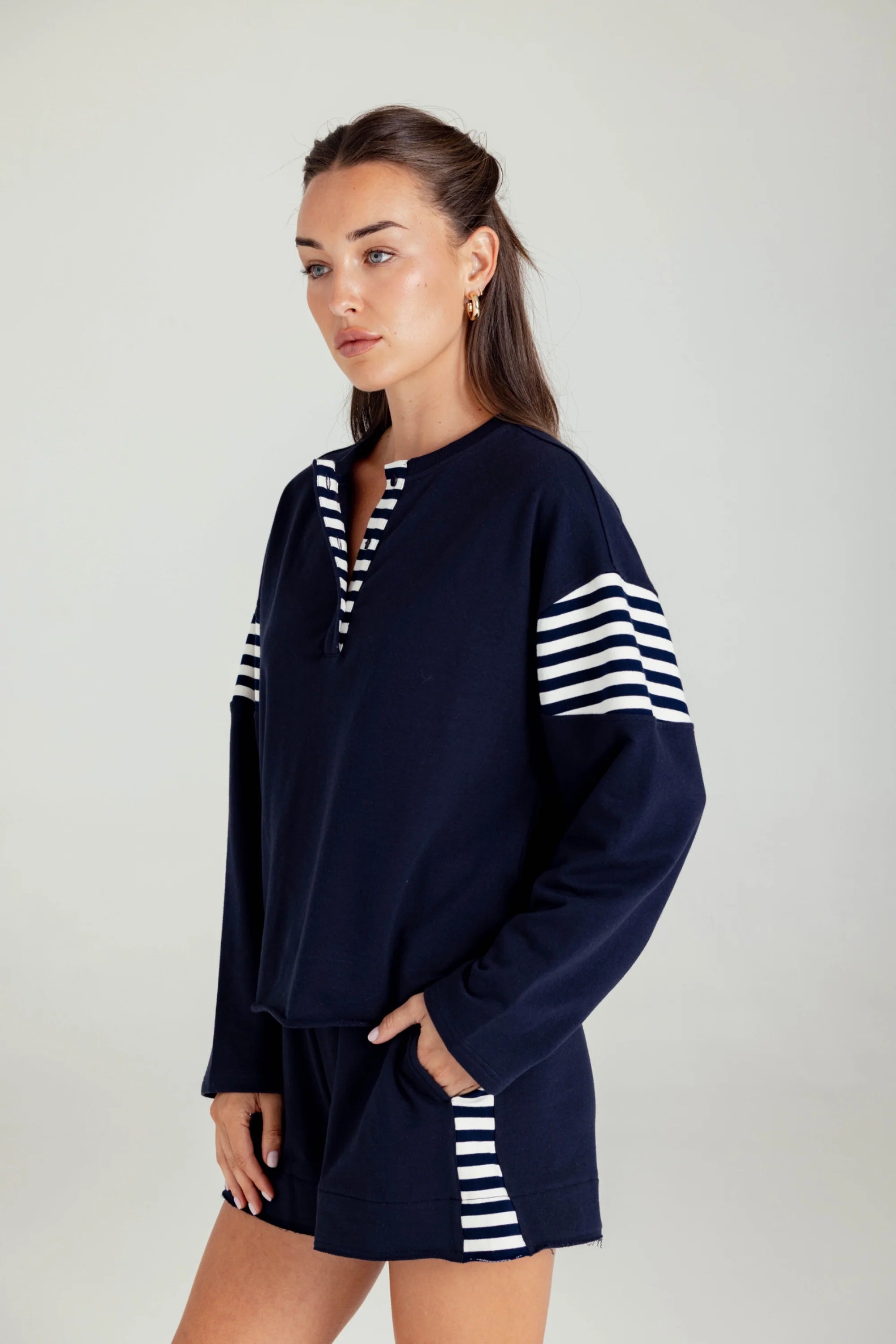 Woman wearing a navy blue outfit with white stripes on a plain background