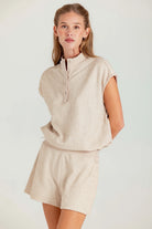 Woman wearing a beige outfit with a matching top and shorts on a white background