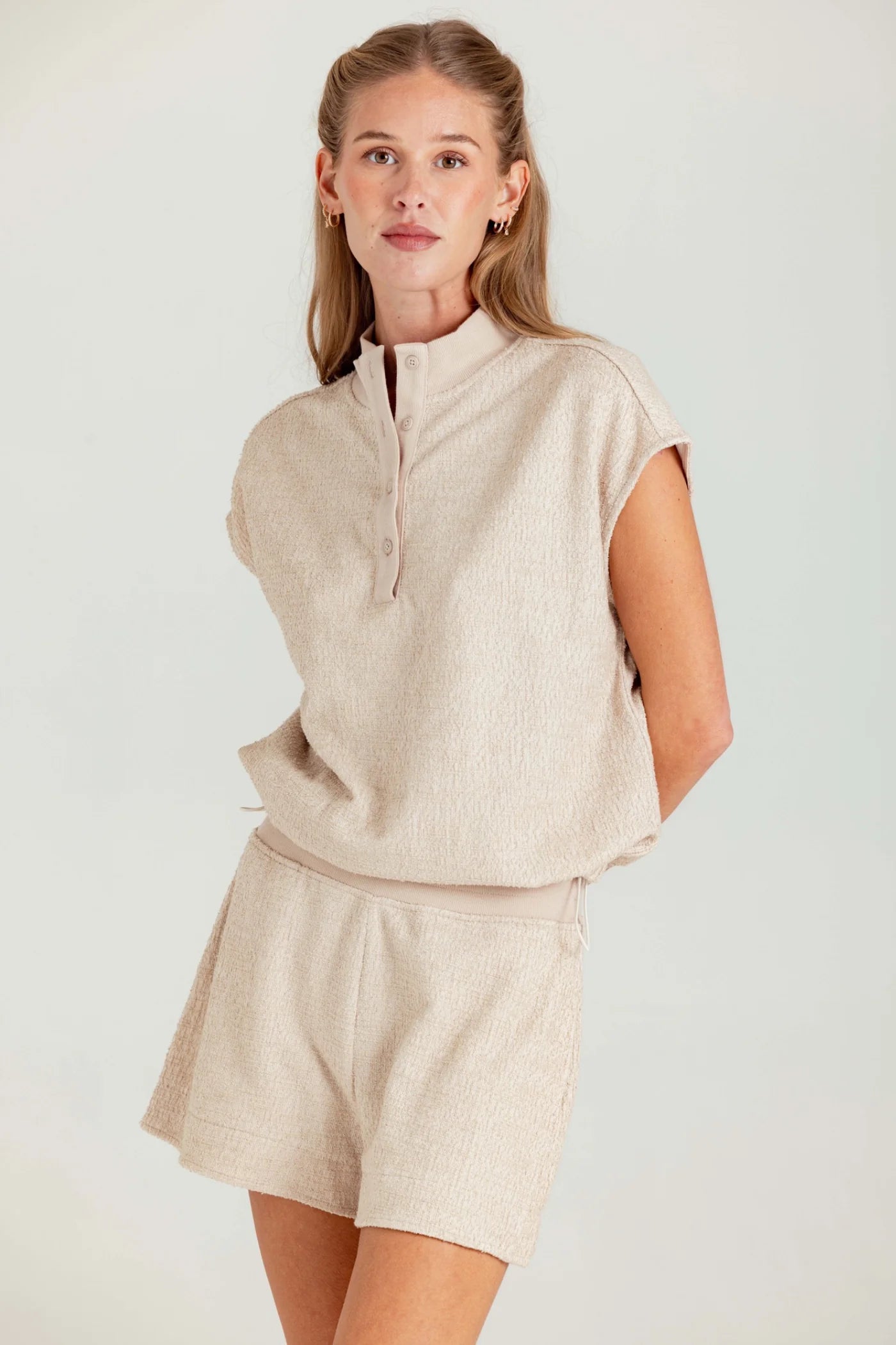 Woman wearing a beige outfit with a matching top and shorts on a white background