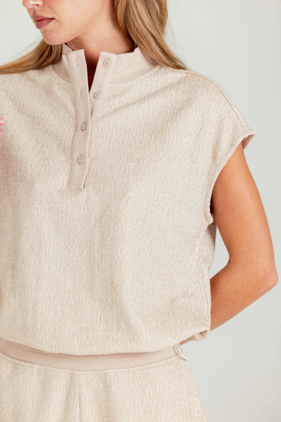 Beige sleeveless top worn by a person on a light gray background