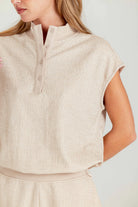 Beige sleeveless top worn by a person on a light gray background