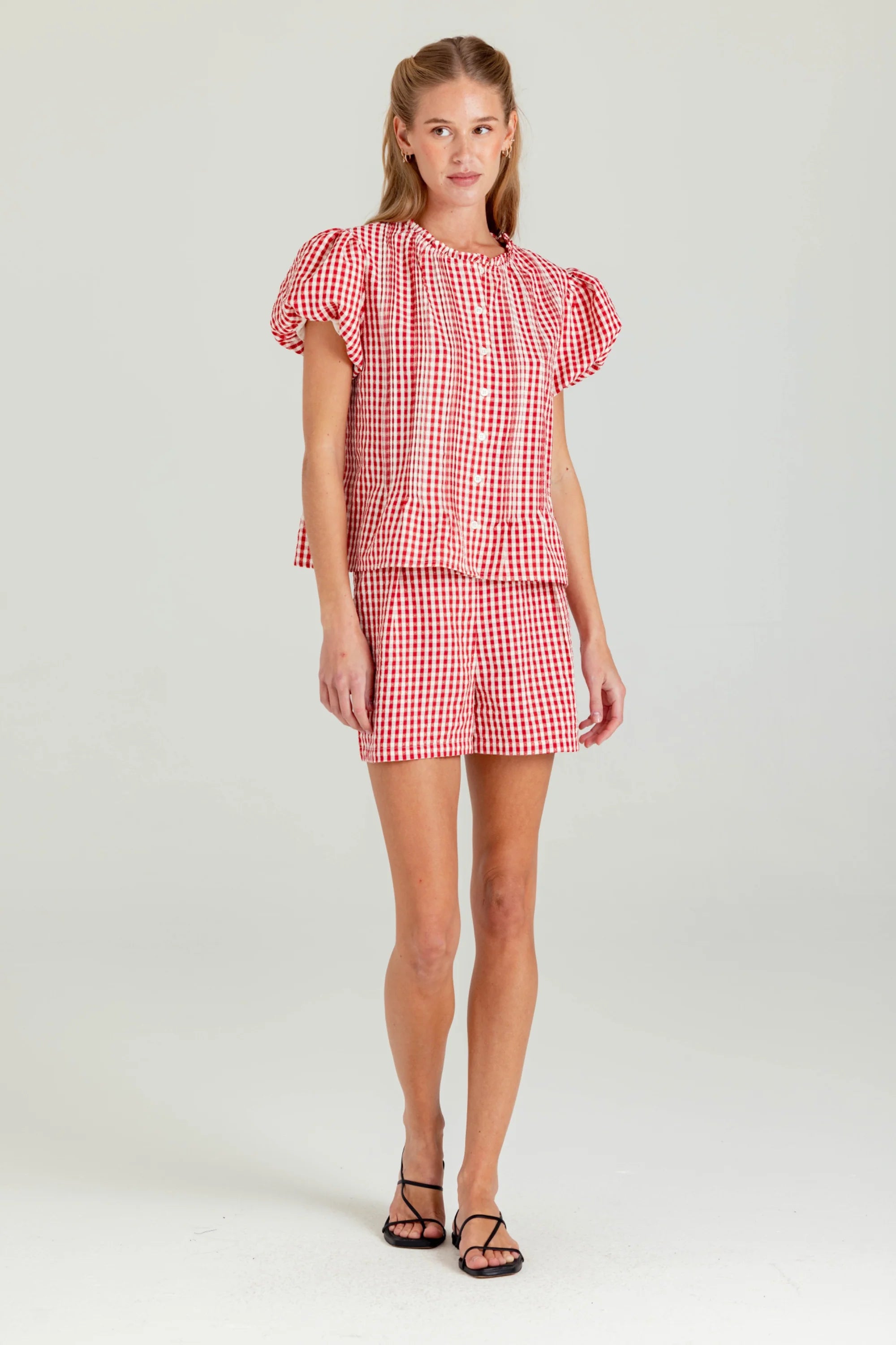 Woman wearing a red and white checkered outfit on a plain background