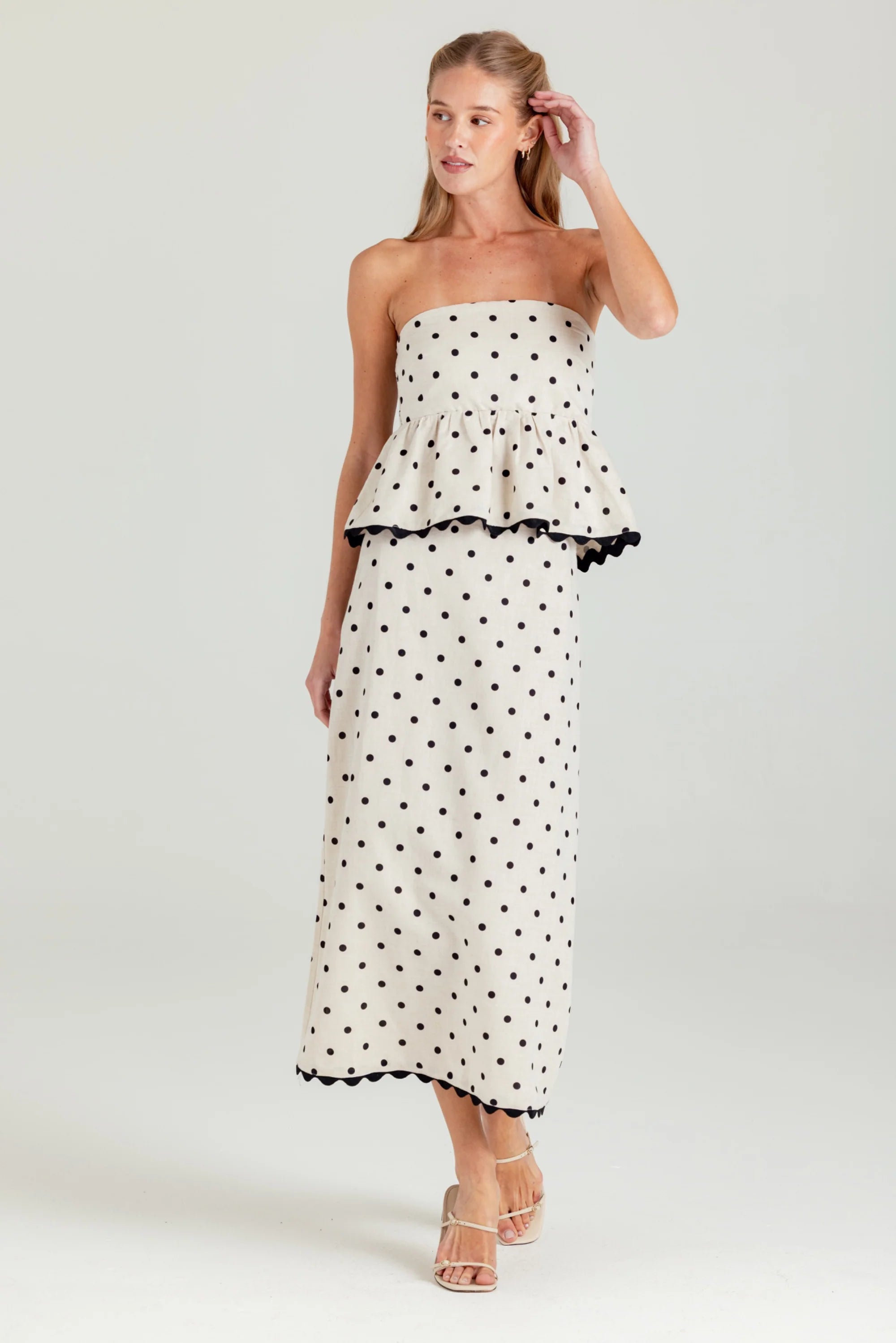 Woman wearing a strapless polka dot dress on a white background