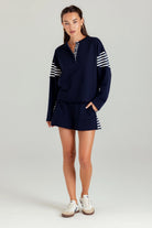 Woman wearing a navy outfit with white stripes on a gray background