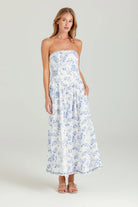 Woman wearing a strapless floral dress on a plain background