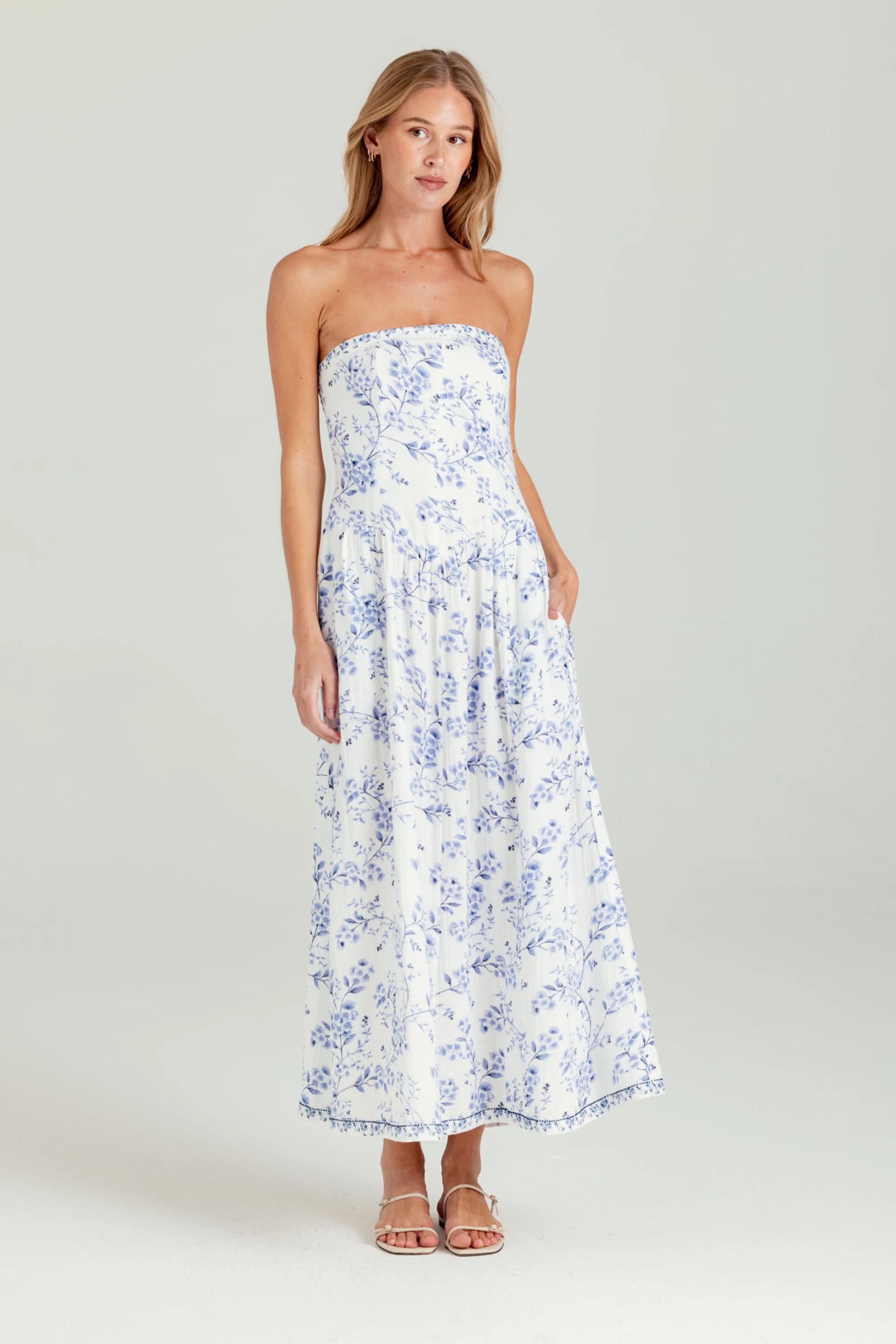 Woman wearing a strapless floral dress on a plain background