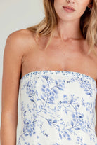 Woman wearing a strapless dress with blue floral pattern on a plain background