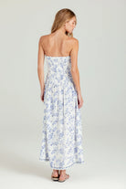 Woman wearing a strapless floral dress on a plain background