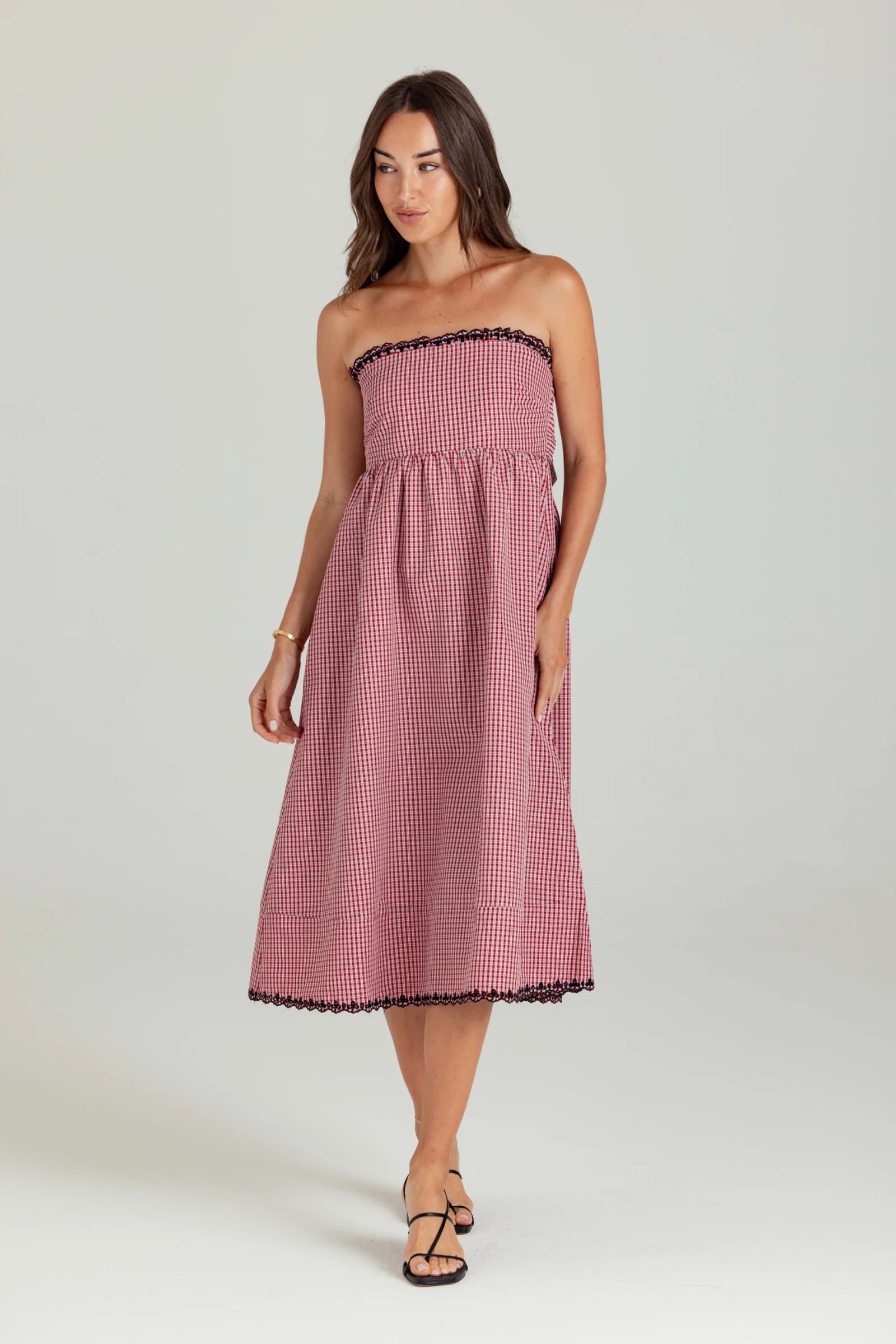 Woman wearing a strapless pink gingham dress on a white background
