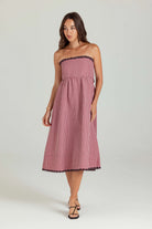 Woman wearing a strapless pink gingham dress on a white background