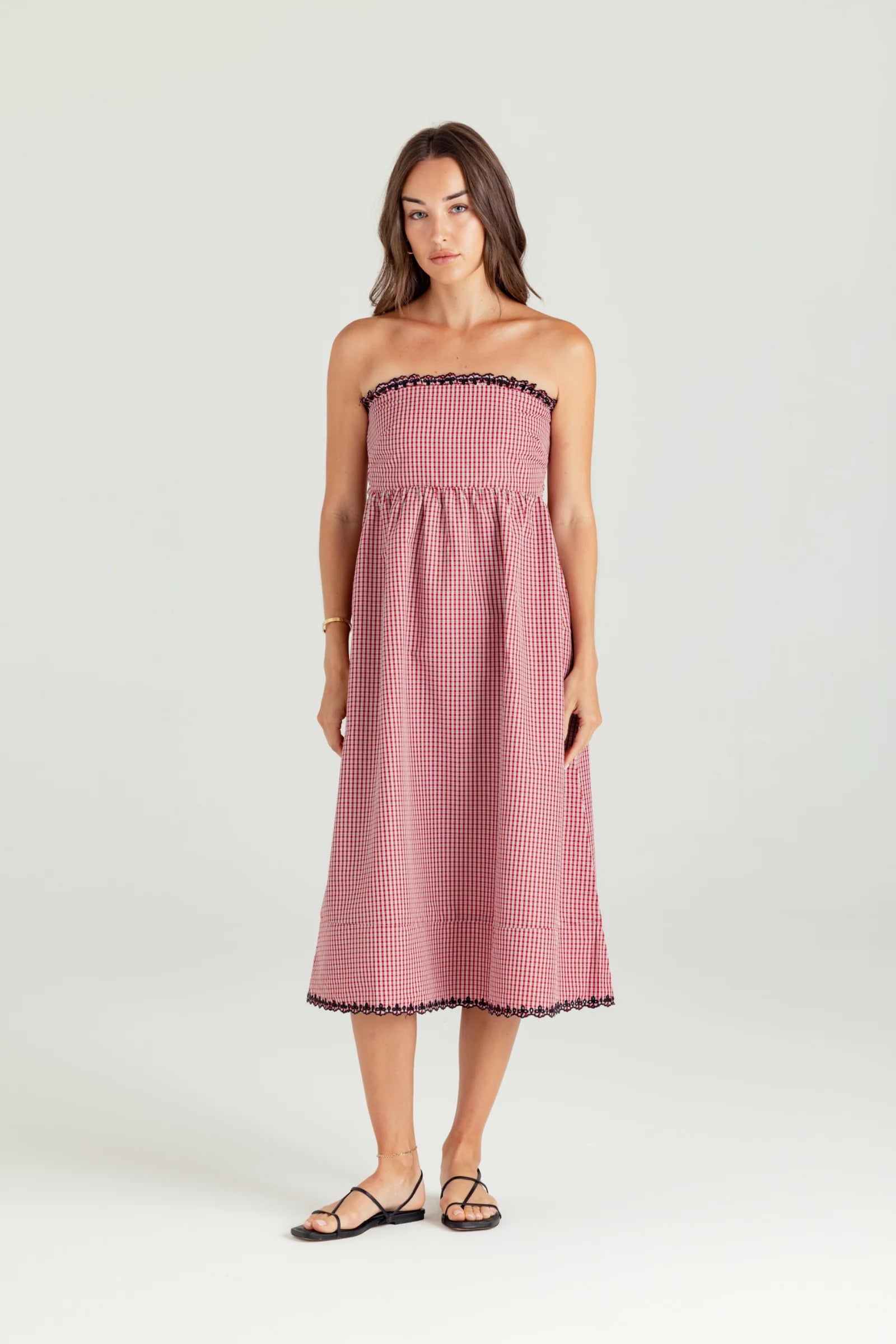 Woman wearing a pink strapless dress with black trim on a white background