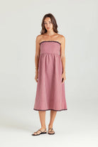 Woman wearing a pink strapless dress with black trim on a white background