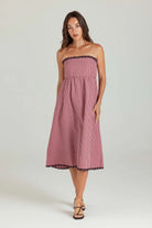 Woman wearing a strapless pink gingham dress on a white background