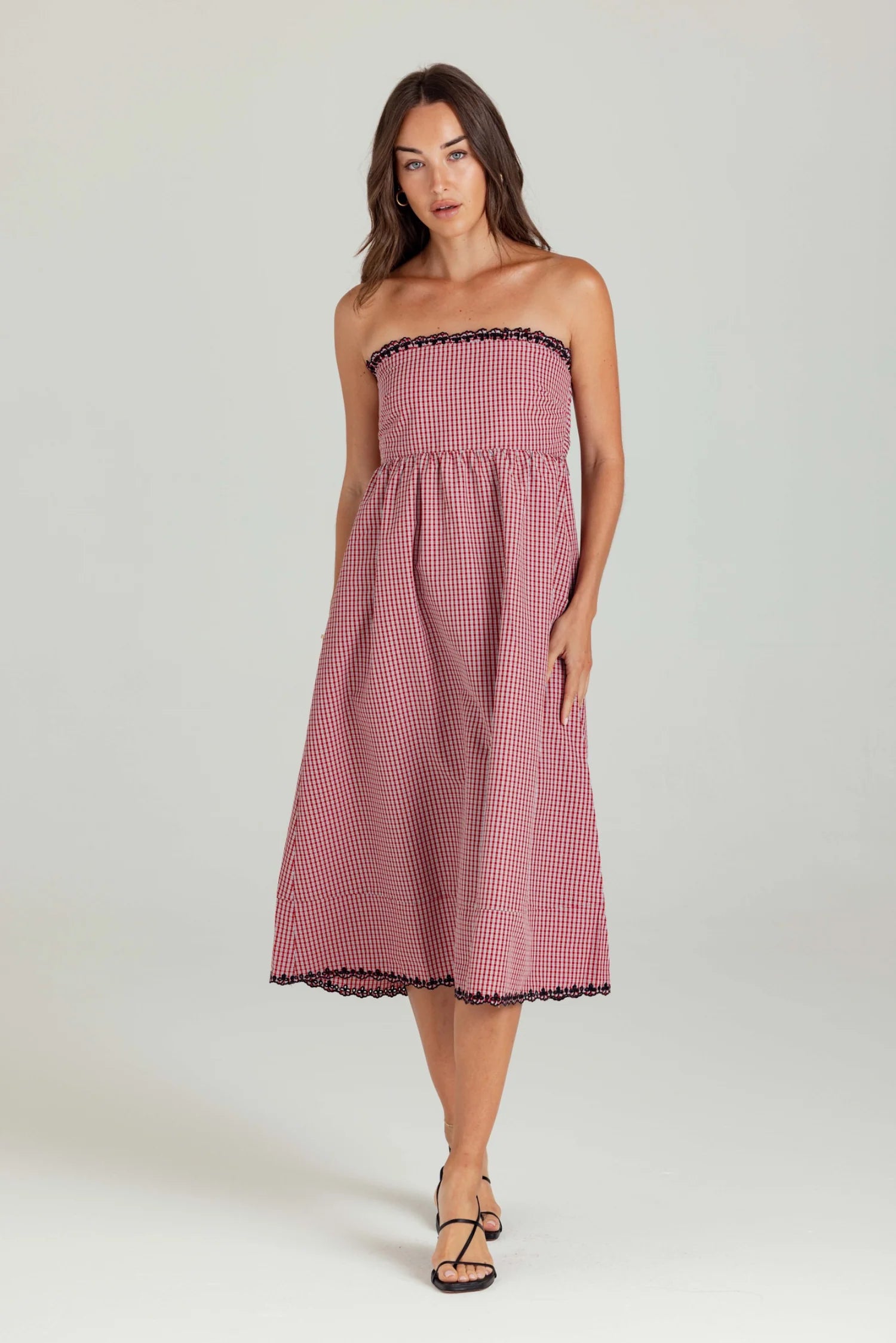 Woman wearing a strapless pink gingham dress on a white background