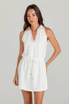 Woman wearing a white dress with pink accents on a plain background