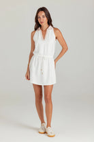 Woman wearing a white sleeveless dress on a plain background