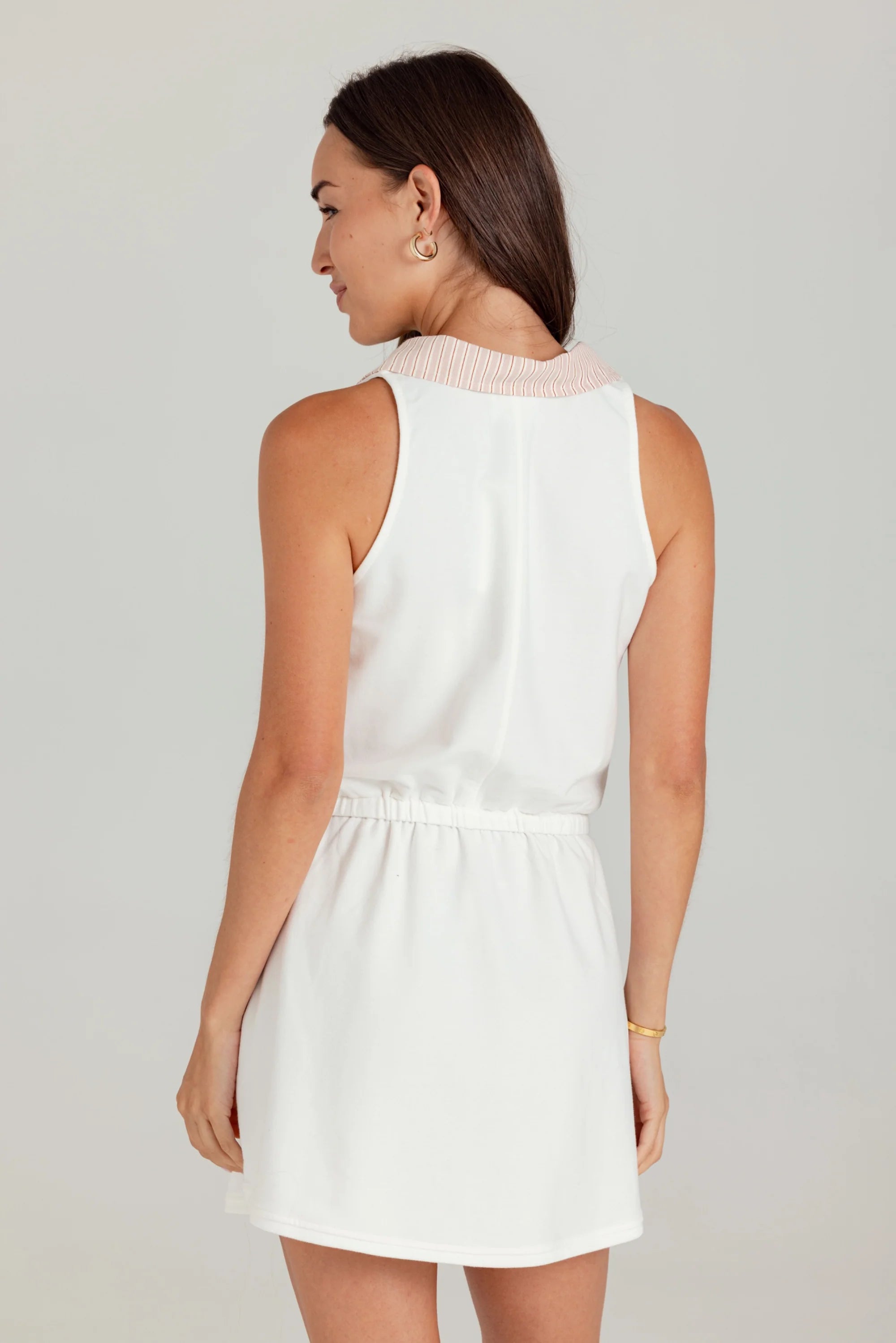 Woman wearing a white sleeveless dress on a plain background