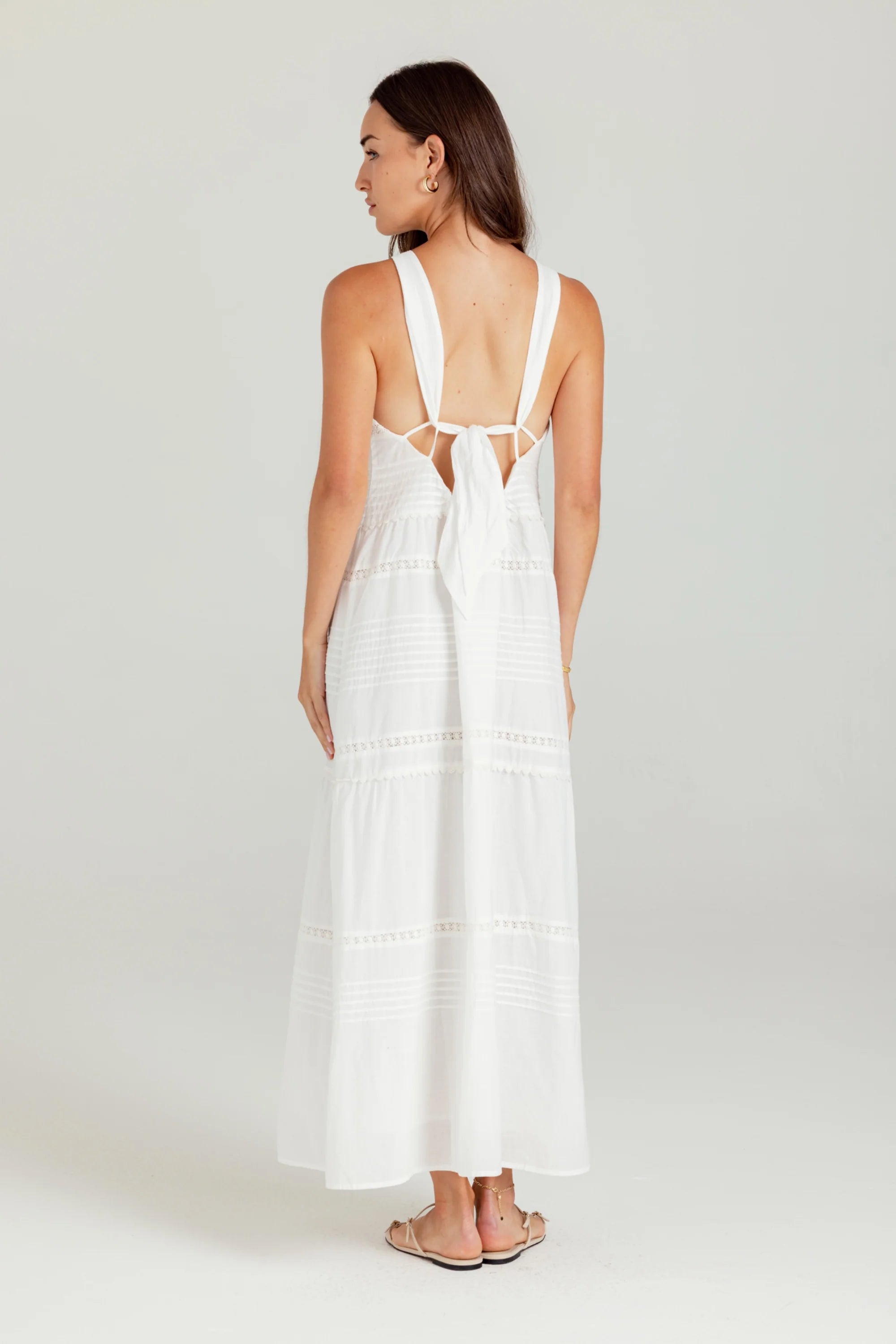 Woman wearing a white dress with thin straps on a plain background