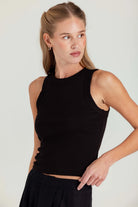 Woman wearing a black sleeveless top against a plain background