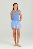 Woman wearing a blue tank top and shorts set on a white background