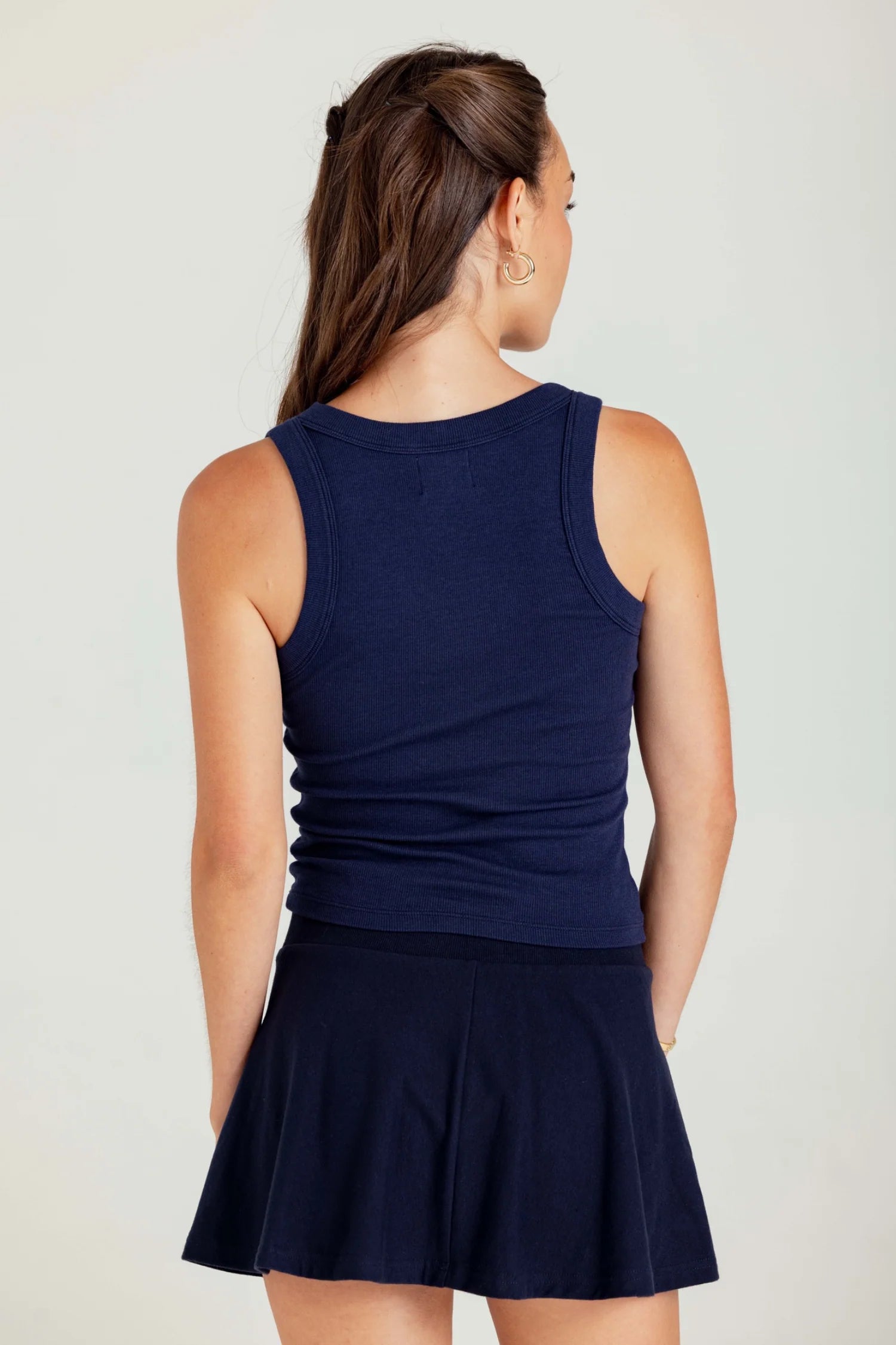 Woman wearing a navy blue sleeveless top and skirt set on a plain background