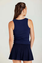 Woman wearing a navy blue sleeveless top and skirt set on a plain background