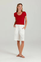 Woman wearing a red top and white shorts on a light gray background