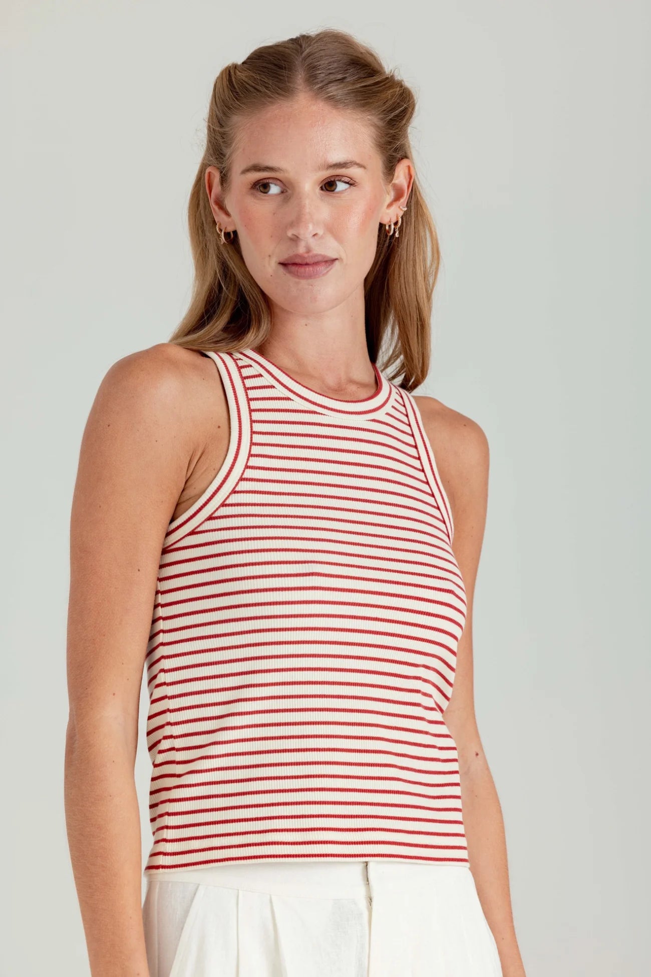 Woman wearing a red and white striped tank top against a plain background