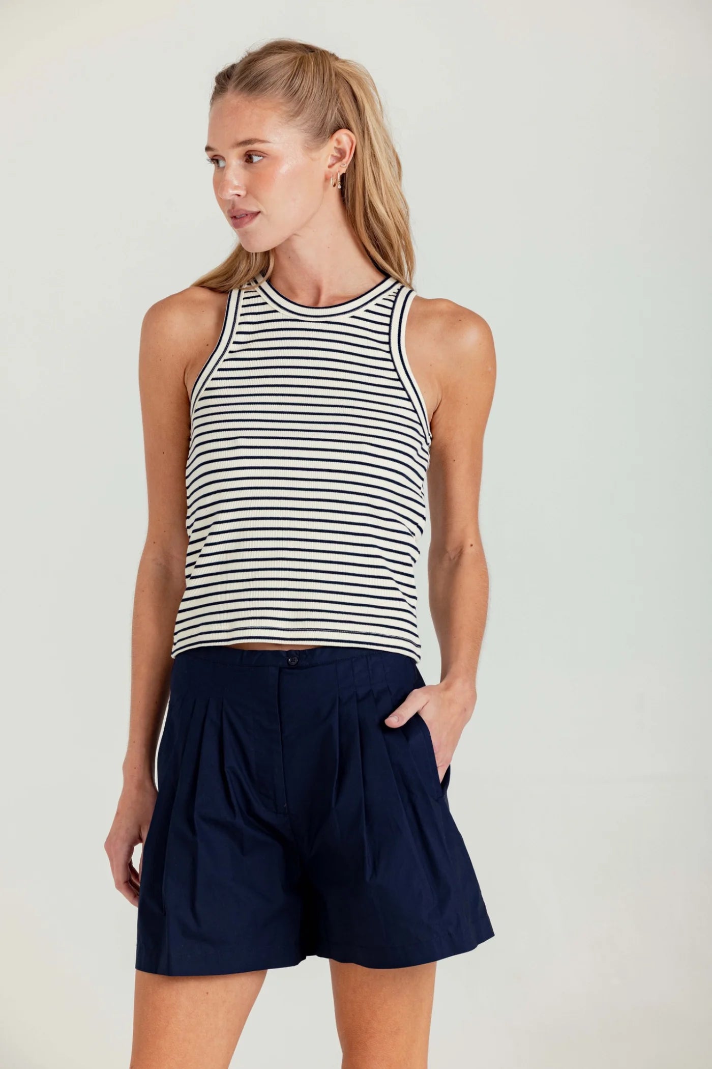 Woman wearing a striped tank top and navy shorts on a white background