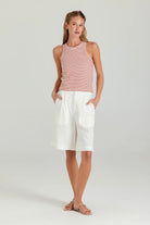 Woman wearing a striped tank top and white shorts on a plain background