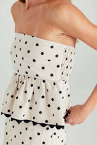Woman wearing a strapless polka dot dress with a plain background