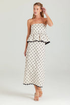 Woman wearing a strapless polka dot dress on a white background