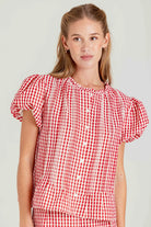 Woman wearing a red and white checkered blouse against a plain background