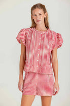 Woman wearing a red and white checkered dress against a plain background