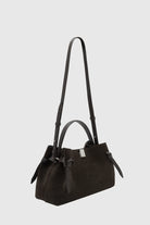 Black handbag with a strap on a light gray background