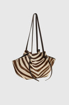 Zebra-striped handbag with black straps on a light gray background