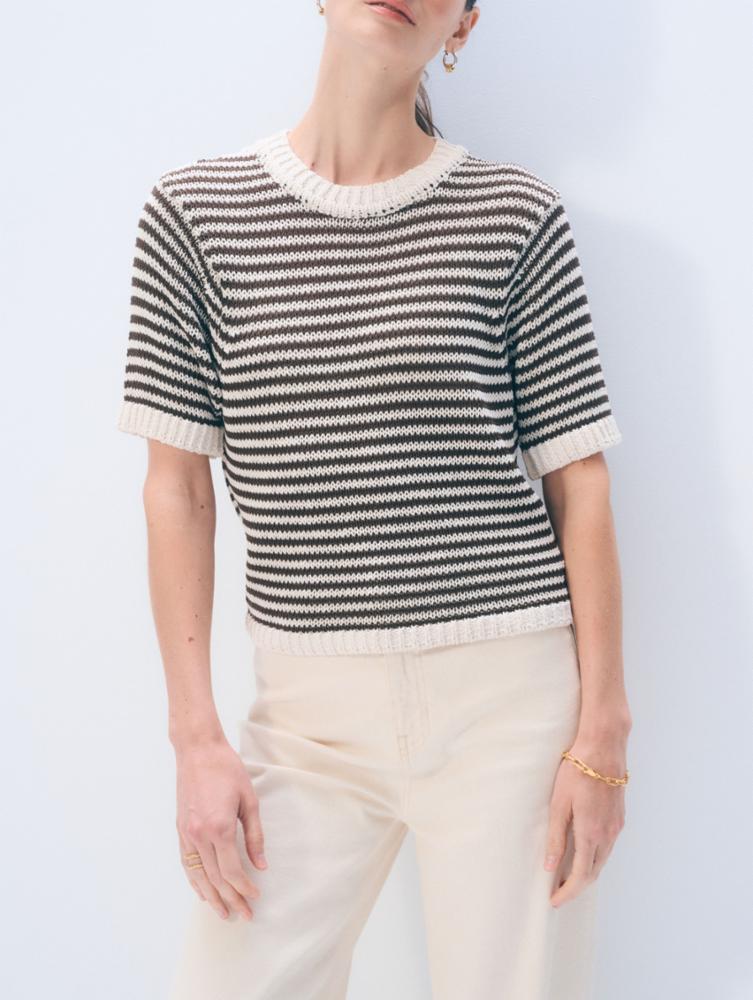 Person wearing a black and white striped sweater with a plain background