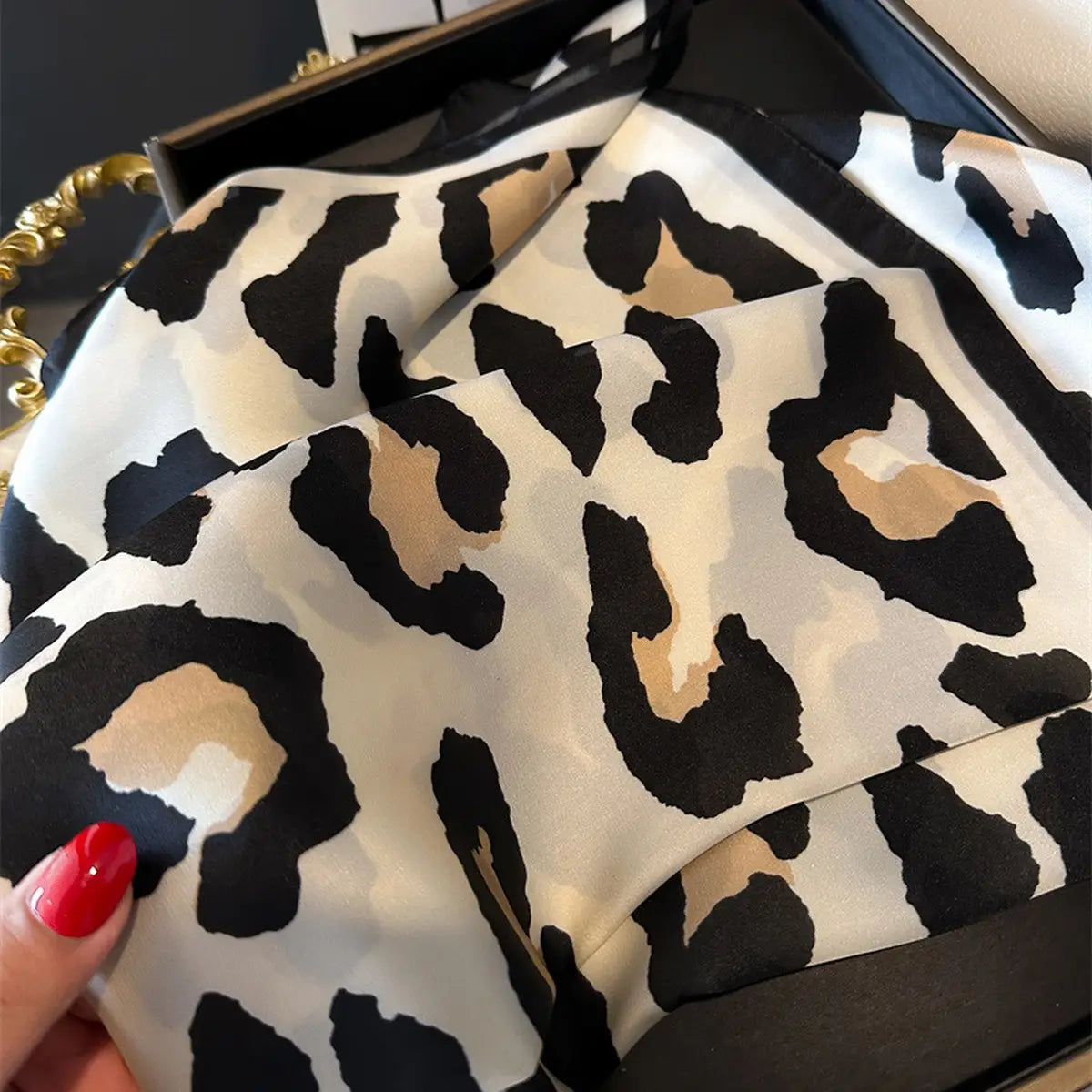 Leopard print fabric held by a hand with red nail polish.