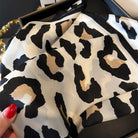 Leopard print fabric held by a hand with red nail polish.