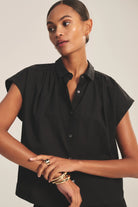 Woman wearing a black sleeveless blouse against a neutral background