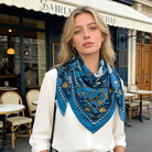 Woman wearing a blue patterned scarf in an outdoor cafe setting