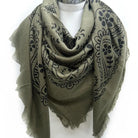 Green scarf with black patterns on a mannequin against a white background