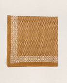 Brown fabric square with white floral pattern on a light beige background